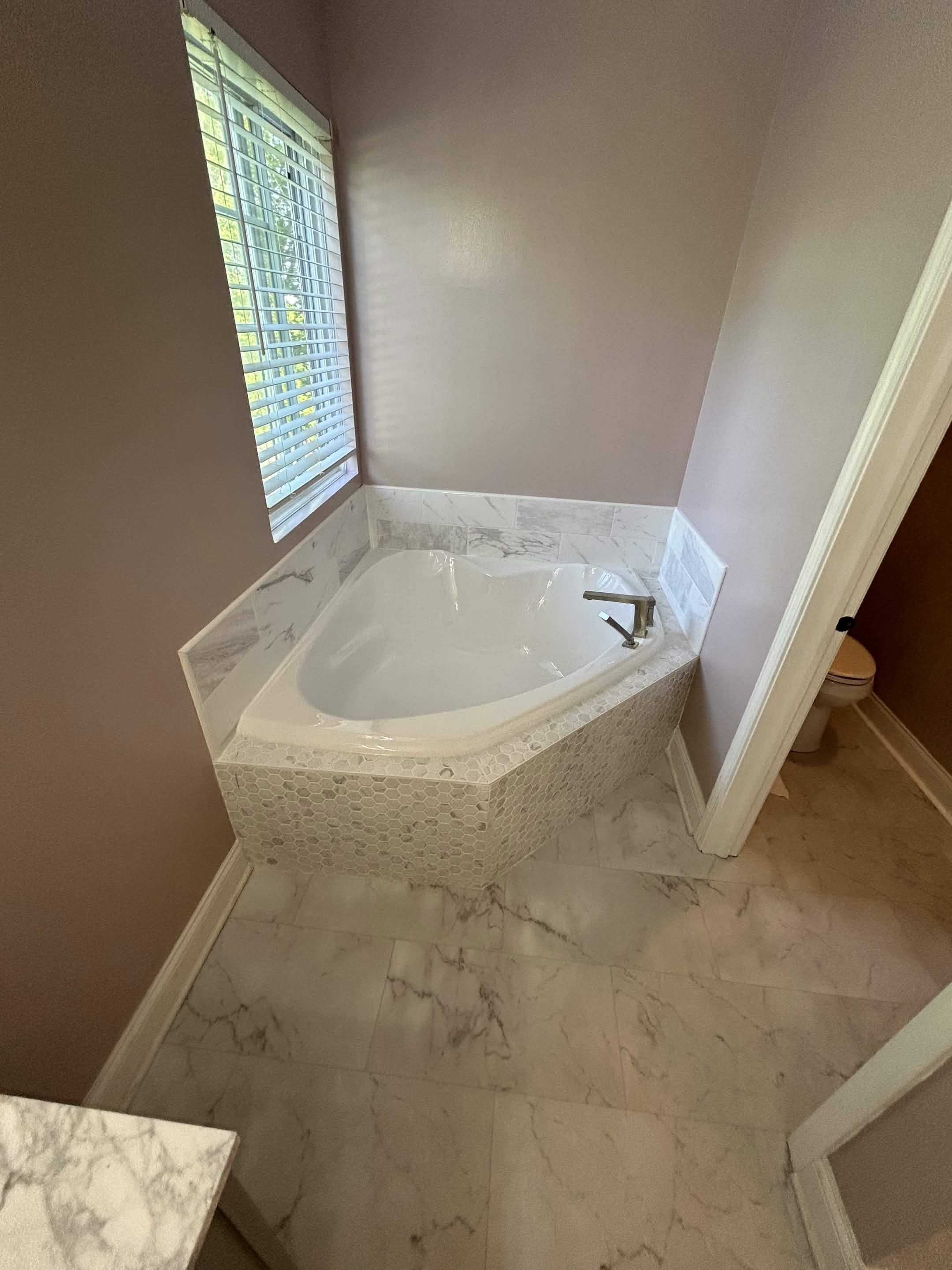 Marble corner tub with hex tile surround